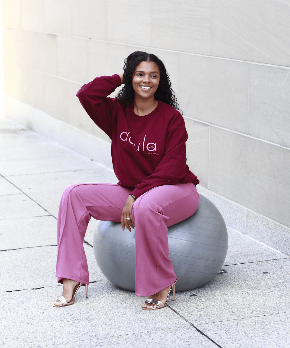 A mother sitting on a medicine ball smiling after giving her inspiring testimony about the LiM Method changing the game for pelvic floor health. 