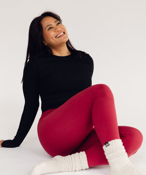 Woman in a trendy workout outfit sitting on the ground smiling after her LiM Method Movement session to strengthen her pelvic floor muscles. 